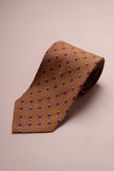 Dark champagne coloured tie with a subtle red geometric floral pattern