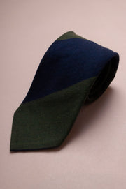 Two-tone green and navy silk and wool tie on a beige background