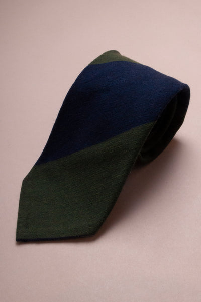 Two-tone green and navy silk and wool tie on a beige background